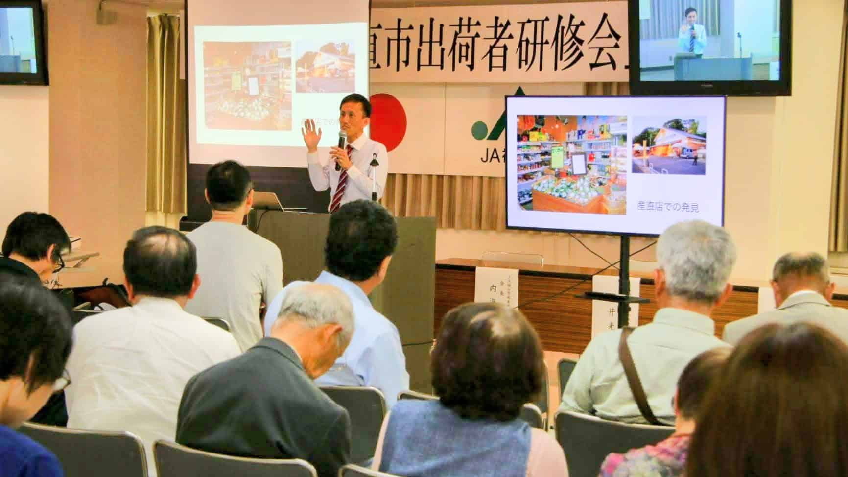 JA福山市の出荷者向け研修で、売場事例をモニターに映しながら商品の魅せ方を解説している様子