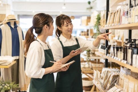 売り場で、スタッフ同士が商品棚を見ながら会話